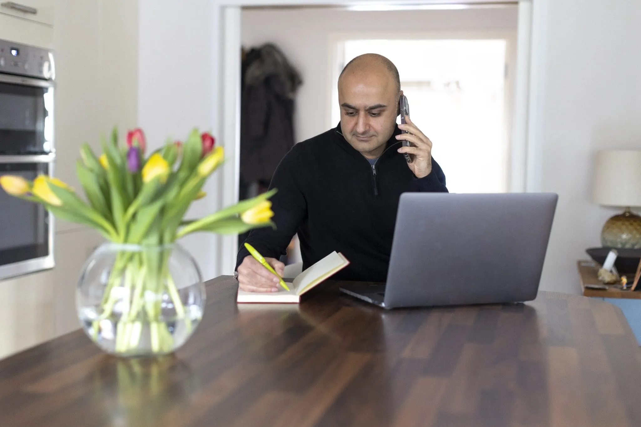 Person working from home at a desk with a laptop in a bright, casual workspace